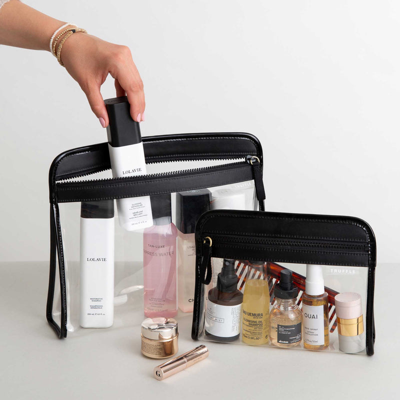 A person packing a black Clarity Pouch Large and Small toiletry bag, containing various beauty products.