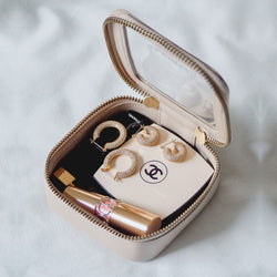 Truffle Clarity Petite Case trimmed in brown leather, filled with lipsticks, blush and earrings.