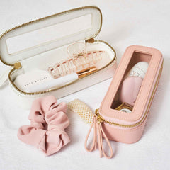 Truffle Mini Jetset Cases packed with beauty items on a white bedspread. 