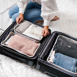 Woman packing clothes into Truffle Clarity Packing Cubes.